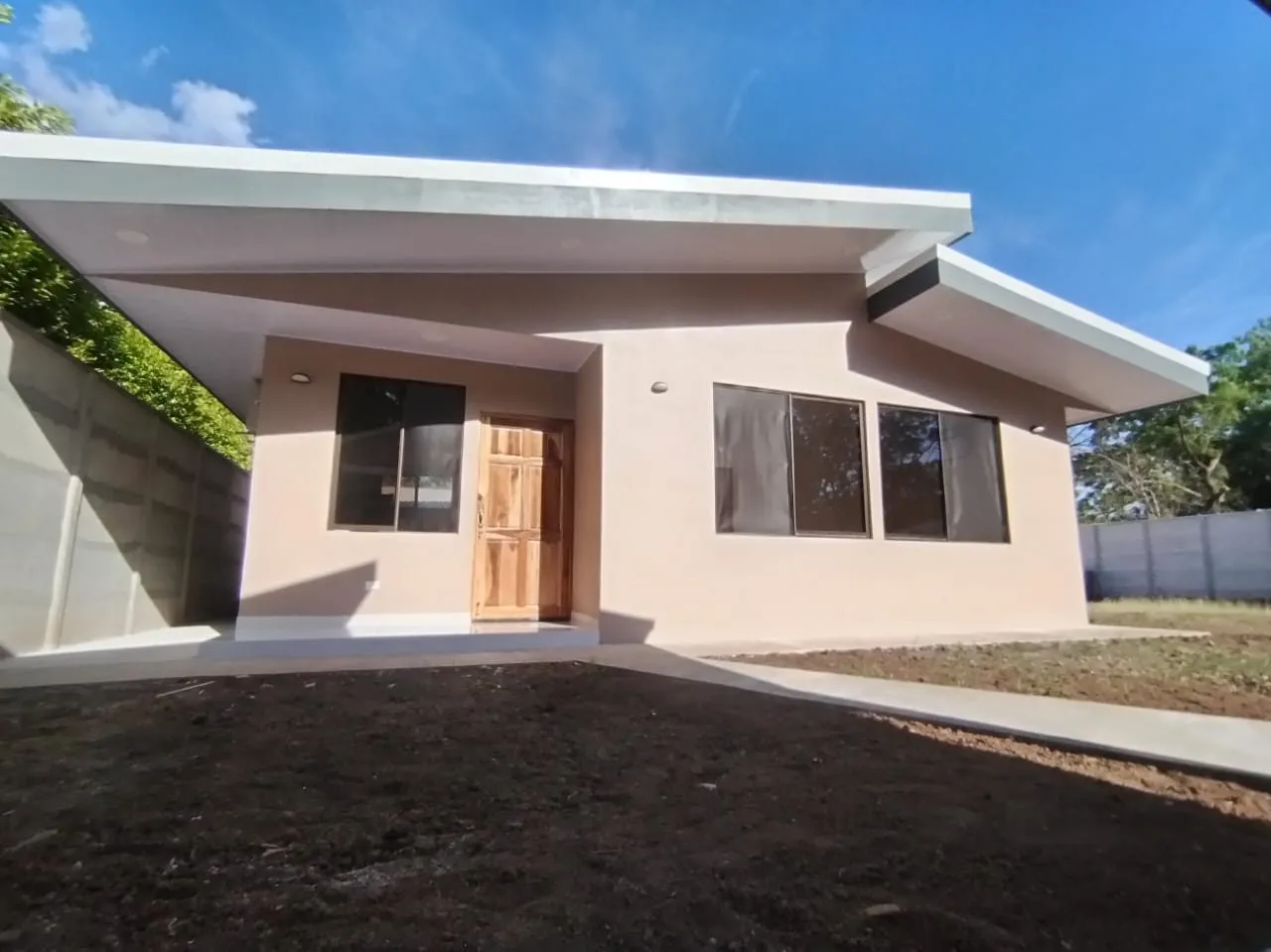 Fachada de la casa terminada, con puerta principal de madera